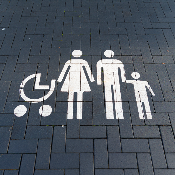 Symbol na chodniku przedstawiający wózek dziecięcy, kobietę i mężczyznę trzymającego za rękę dziecko.