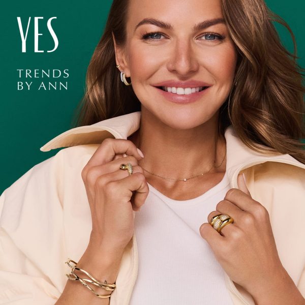Anna Lewandowska prezentuje kolczyki, pierścionki, naszyjnik i bransoletki YES na zielonym tle z napisem „Trends by Ann”.